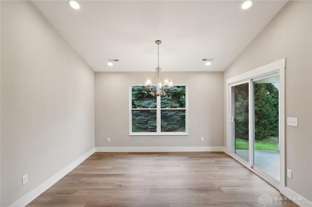 unfurnished dining area featuring an inviting chandelier and light hardwood / wood-style floors