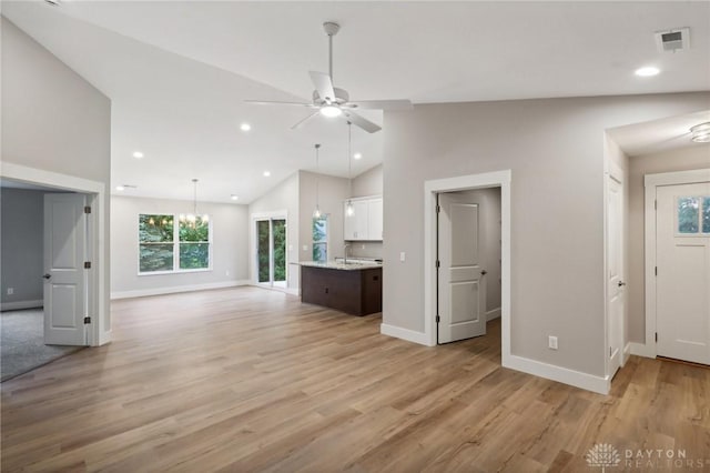 unfurnished living room featuring a healthy amount of sunlight, sink, light hardwood / wood-style floors, and ceiling fan with notable chandelier