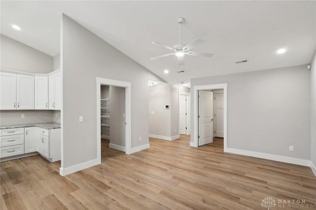 interior space with light stone countertops, white cabinets, ceiling fan, and light hardwood / wood-style flooring