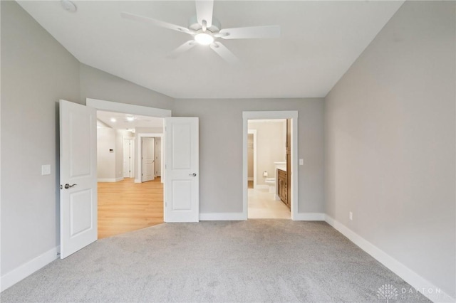 unfurnished bedroom with ensuite bathroom, vaulted ceiling, light carpet, and ceiling fan