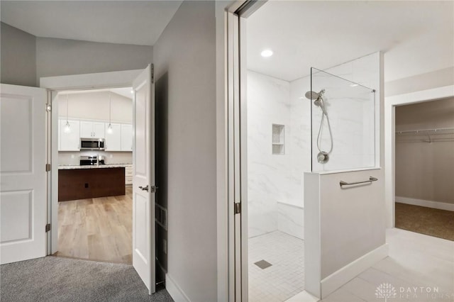 bathroom featuring vaulted ceiling and a tile shower