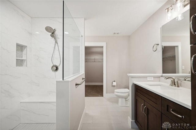 bathroom with vanity, a tile shower, and toilet