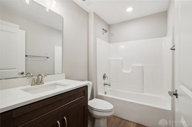 full bathroom featuring vanity, hardwood / wood-style flooring, bathtub / shower combination, and toilet