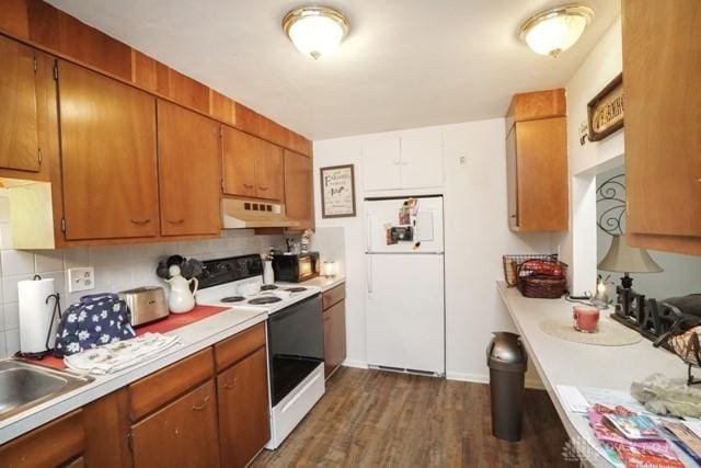 kitchen featuring dark wood-type flooring, white appliances, and decorative backsplash