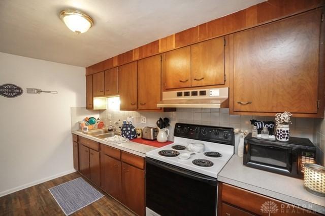 kitchen with sink, decorative backsplash, range with electric cooktop, and dark hardwood / wood-style floors