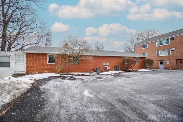 snow covered rear of property with central AC unit