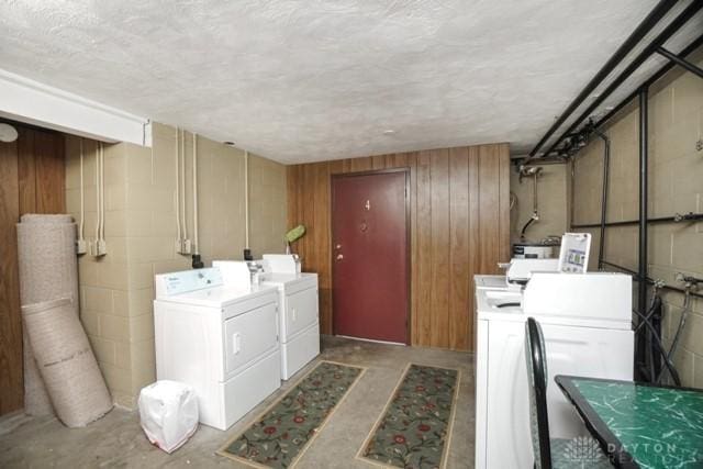 laundry area with washing machine and clothes dryer and wooden walls