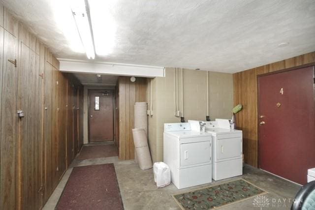 washroom with washing machine and dryer and wood walls