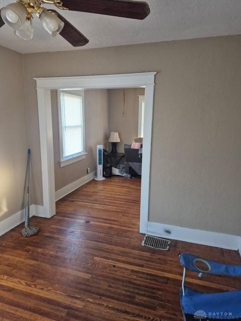 interior space with ceiling fan, a textured ceiling, and dark hardwood / wood-style flooring