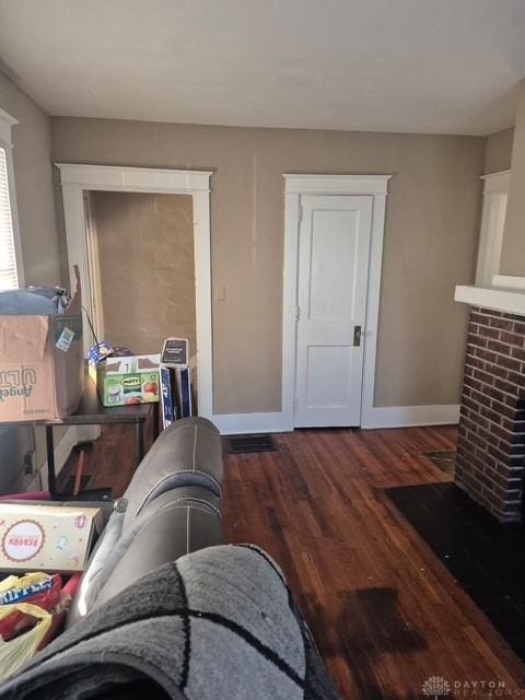 interior space with a brick fireplace and dark wood-type flooring