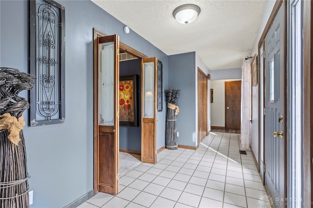 hallway with light tile patterned flooring and a textured ceiling