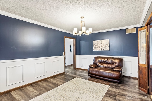 sitting room featuring crown molding, a chandelier, dark wood-type flooring, and a textured ceiling