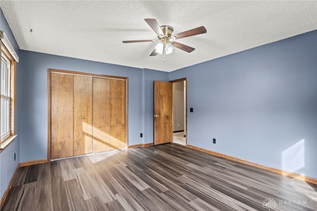 unfurnished bedroom with ceiling fan, dark hardwood / wood-style floors, a textured ceiling, and a closet