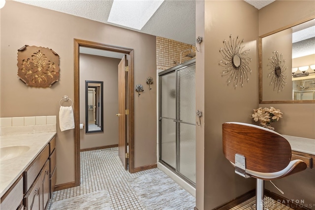 bathroom with walk in shower, vanity, a skylight, and a textured ceiling