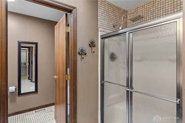 bathroom with tile patterned flooring, a shower with door, and a textured ceiling