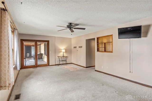 spare room with a textured ceiling, light colored carpet, and ceiling fan