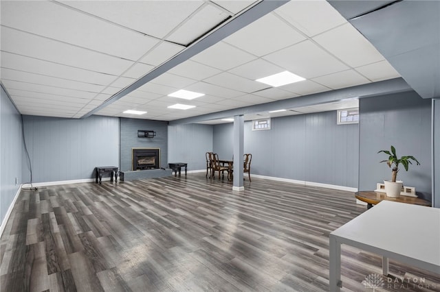 basement with a drop ceiling, hardwood / wood-style flooring, and a fireplace