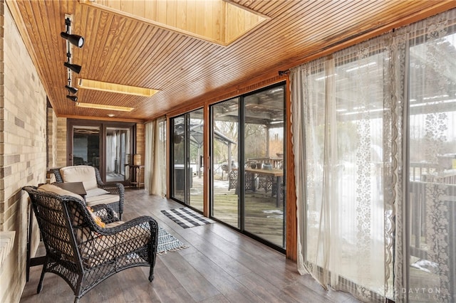 sunroom featuring track lighting, wooden ceiling, and a skylight