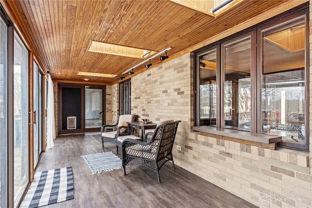 sunroom / solarium with rail lighting, a skylight, and wooden ceiling