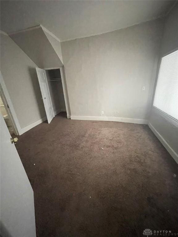 unfurnished bedroom featuring dark carpet and a closet