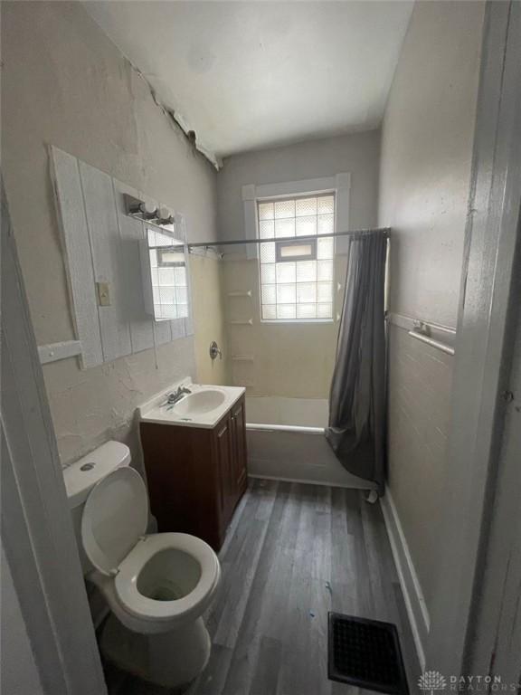 full bathroom with vanity, wood-type flooring, toilet, and shower / bath combo with shower curtain