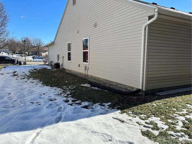 snow covered property with central air condition unit