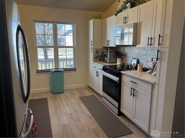 kitchen featuring stainless steel fridge, white cabinetry, backsplash, range with electric cooktop, and light hardwood / wood-style floors