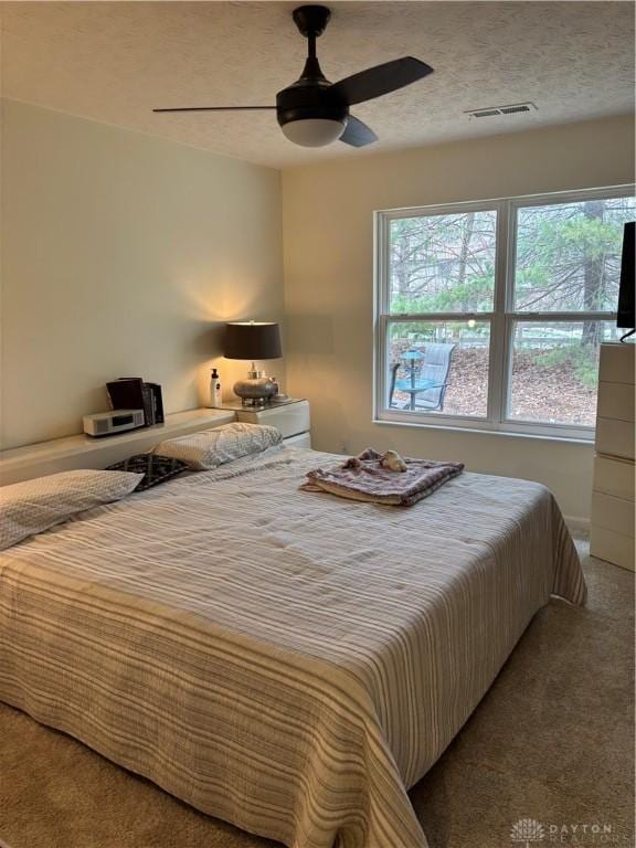 bedroom featuring ceiling fan, carpet floors, and a textured ceiling