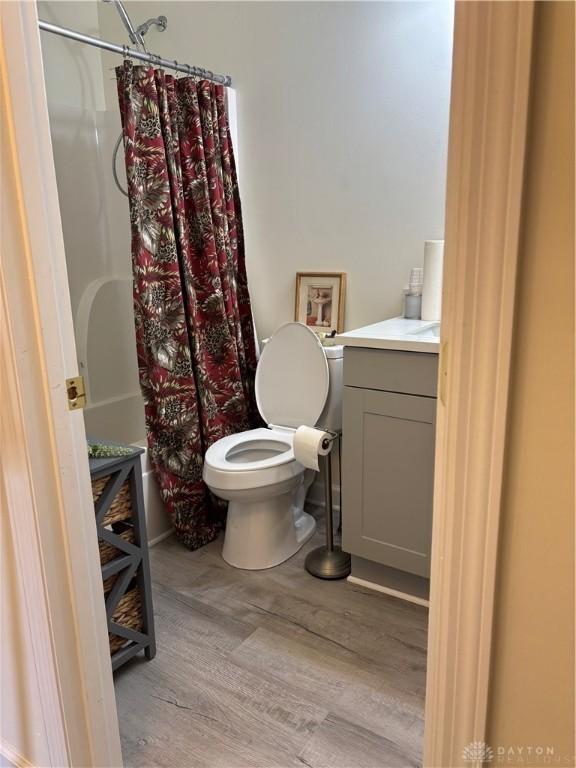 full bathroom with vanity, hardwood / wood-style floors, shower / bath combo, and toilet