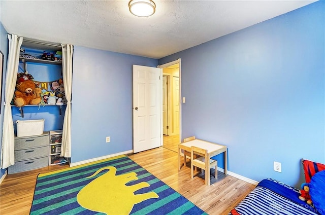 recreation room featuring wood-type flooring and a textured ceiling