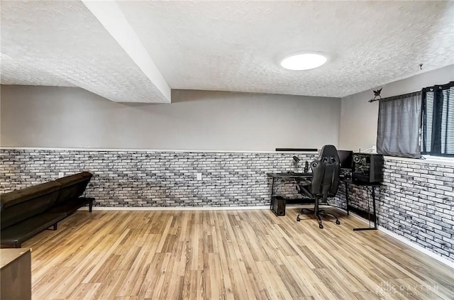 office space featuring brick wall, a textured ceiling, and light wood-type flooring