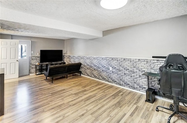 office with brick wall, a textured ceiling, and light wood-type flooring