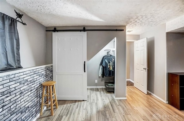 interior space with a barn door, a textured ceiling, and light hardwood / wood-style floors