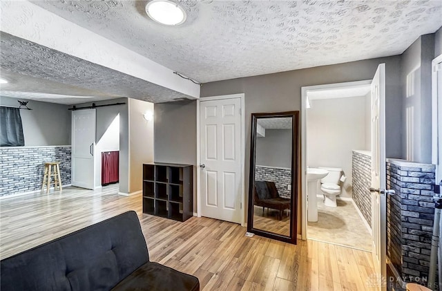 interior space featuring a barn door, light hardwood / wood-style floors, and a textured ceiling