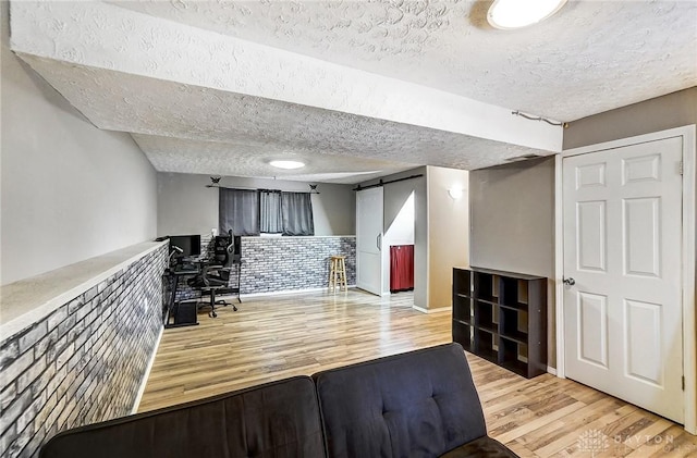 unfurnished office featuring light hardwood / wood-style flooring, a barn door, and a textured ceiling