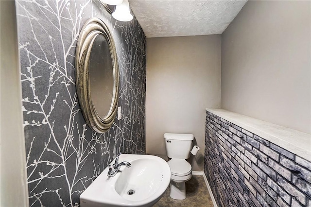 bathroom with toilet, sink, and a textured ceiling