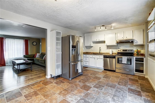 kitchen with sink, white cabinetry, a textured ceiling, stainless steel appliances, and backsplash