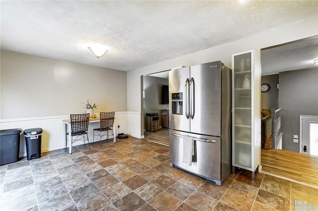 kitchen featuring stainless steel fridge with ice dispenser and a textured ceiling