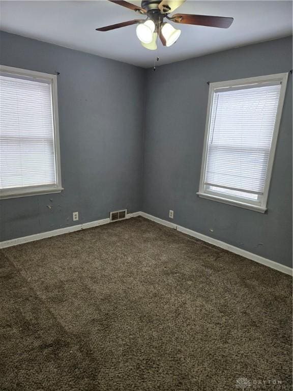 carpeted spare room featuring a wealth of natural light and ceiling fan