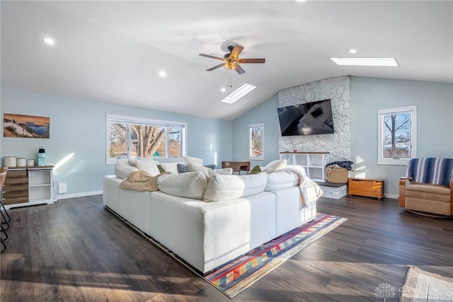 living area with dark wood-type flooring, lofted ceiling with skylight, a wealth of natural light, and baseboards