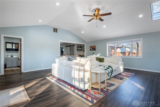 living room with vaulted ceiling with skylight, visible vents, dark wood finished floors, baseboards, and ceiling fan