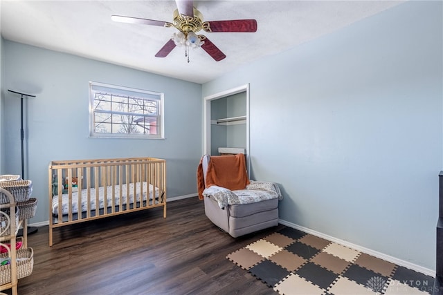 bedroom featuring dark wood-style floors, a closet, a ceiling fan, and baseboards