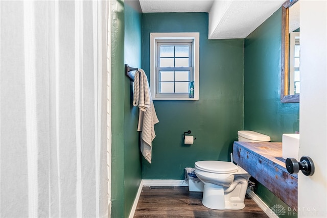 bathroom featuring toilet, visible vents, baseboards, and wood finished floors