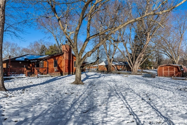 yard covered in snow featuring an outbuilding and a storage unit