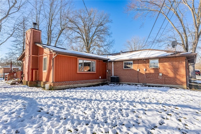 exterior space with brick siding, a chimney, and central air condition unit