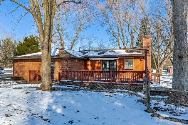 view of front of property with a deck, brick siding, and a chimney