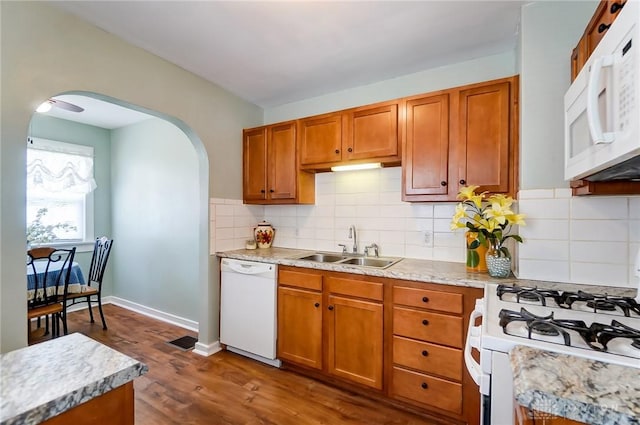 kitchen featuring dark wood-type flooring, white appliances, sink, and decorative backsplash