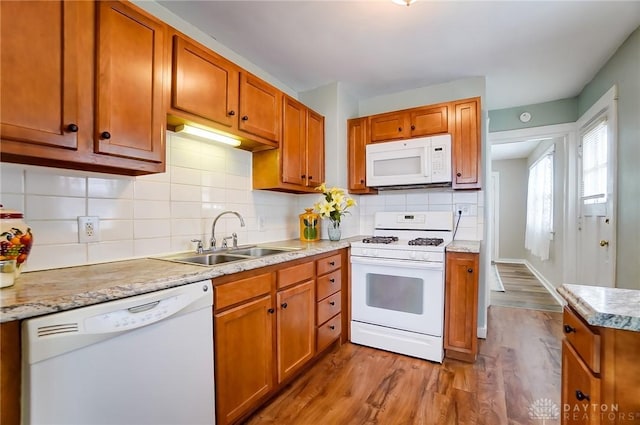 kitchen with hardwood / wood-style flooring, white appliances, sink, and decorative backsplash