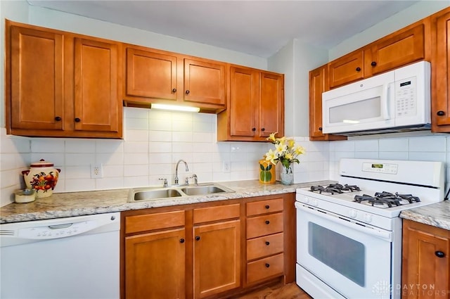 kitchen with light stone countertops, sink, white appliances, and decorative backsplash