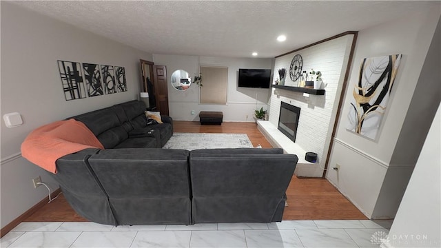 living room featuring a large fireplace, wood-type flooring, and a textured ceiling